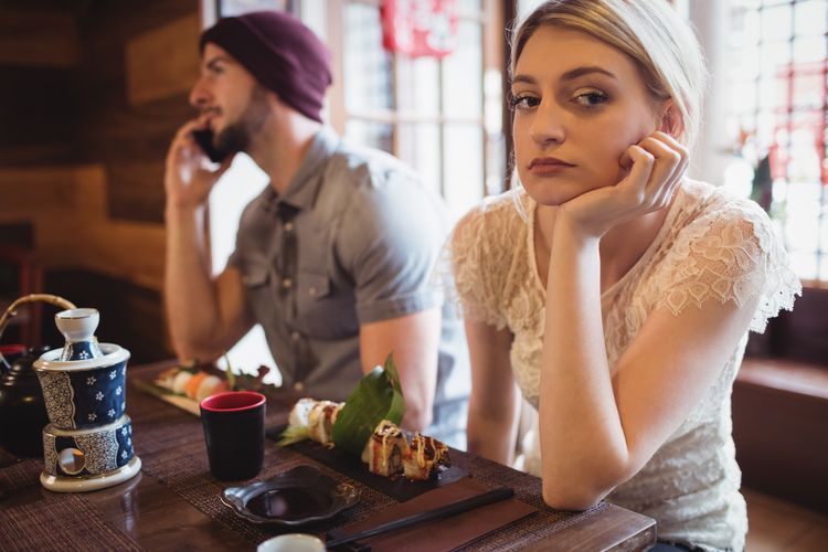 Man ignoring woman while talking on phone in restaurant